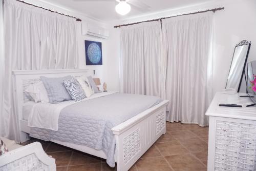 a white bedroom with a white bed and white curtains at The Corals Punta Cana (Mar de los Corales ll ) in Punta Cana