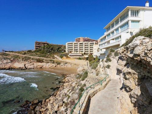 a building on the side of a cliff next to the ocean at Apartamento sobre el mar in Salou