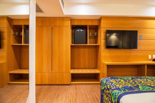 a bedroom with a bed and a tv and wooden cabinets at Arena Copacabana Hotel in Rio de Janeiro