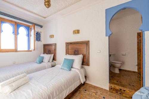 two beds in a room with a toilet at Dar Bleu main in Chefchaouene