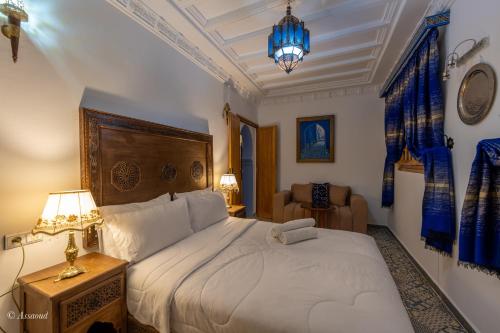 a bedroom with a large white bed with blue curtains at Dar Bleumain in Chefchaouen