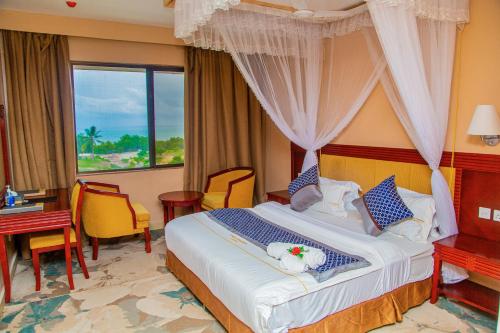 een hotelkamer met een bed, een bureau en een raam bij Luwa Evergreen Hotel in Mtwara
