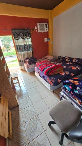 a bedroom with two beds and a chair in it at Hotel Los Chow Chow in Posadas