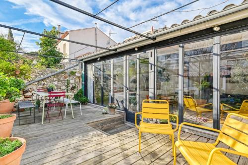 une véranda avec des chaises jaunes sur une terrasse en bois dans l'établissement Maison Maturo - Welkeys, à Marseille