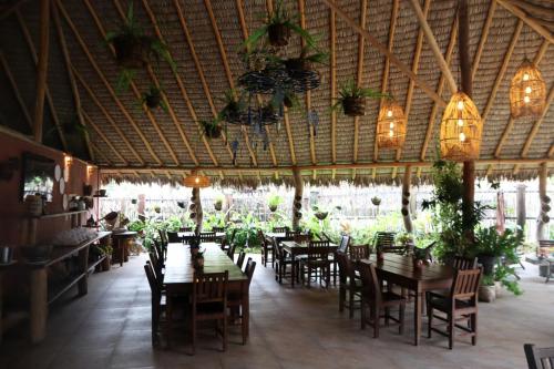 a restaurant with wooden tables and chairs and chandeliers at Pousada Vila Camurim in Atins