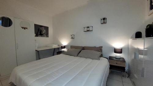 une chambre avec un grand lit blanc et deux lampes dans l'établissement BEACH APPART, à Nice