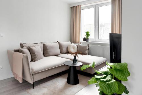 a white living room with a couch and a table at Flatbook - City Center Apartments Scala Moderna in Gdańsk