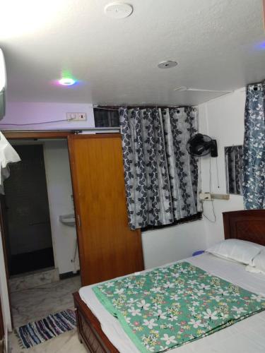 ein kleines Schlafzimmer mit einem Bett und einem Fenster mit Vorhängen in der Unterkunft Cozy homestay in Puducherry