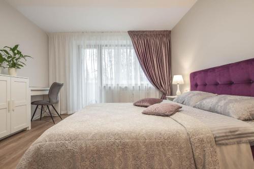 1 dormitorio con 1 cama grande y cabecero púrpura en VAVA apartment, en Klaipėda