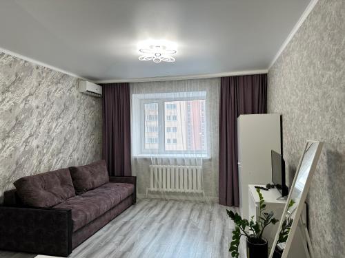 a living room with a couch and a window at Уютная квартира ЖК Сказочный мир город Астана in Astana