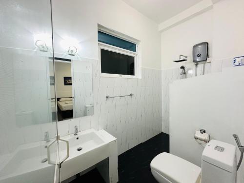 a white bathroom with a sink and a toilet at Jungle Fence in Bentota