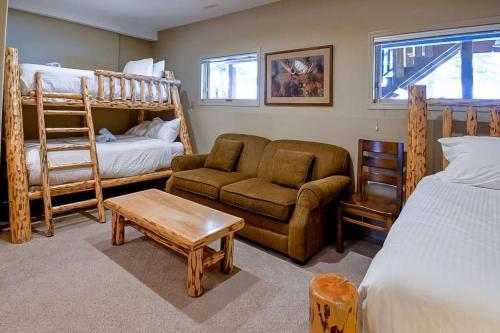 een slaapkamer met een stapelbed en een bank en een stoel bij Thunder Ridge Chalet by Fernie Lodging Company in Fernie