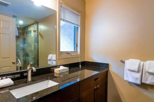 ein Badezimmer mit einem Waschbecken und einem großen Spiegel in der Unterkunft Thunder Ridge Chalet by Fernie Lodging Company in Fernie