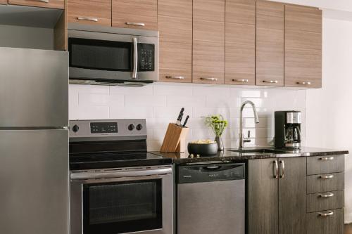 a kitchen with stainless steel appliances and wooden cabinets at Sonder Penny Lane in Montreal