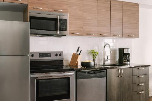 a kitchen with stainless steel appliances and wooden cabinets at Sonder Penny Lane in Montréal