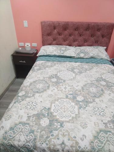 een slaapkamer met een bed met een grote sprei bij Hostal Blue Royal in Quito