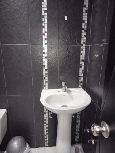 een badkamer met een witte wastafel en een toilet bij Hostal Blue Royal in Quito