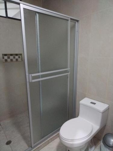 a bathroom with a toilet and a glass shower at Hostal Blue Royal in Quito