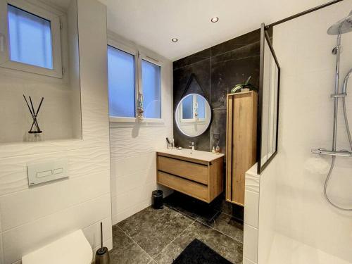 een badkamer met een wastafel en een spiegel bij Maison familiale avec jardin in Aulnay-sous-Bois