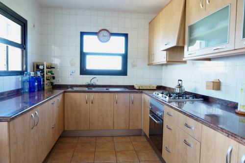 Una cocina con armarios de madera y un fregadero y una ventana. en Casa Sa Playa - Astbury Formentera, en Es Arenals