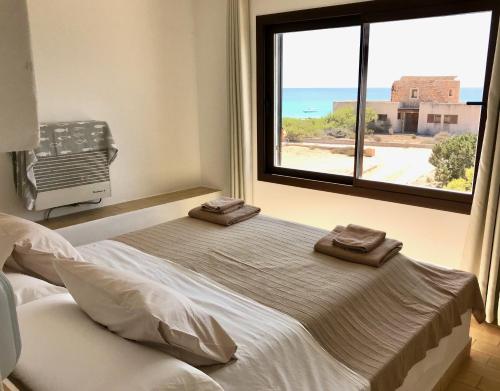 Una cama en un dormitorio con una ventana grande. en Casa Sa Playa - Astbury Formentera, en Es Arenals