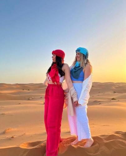 two women are standing in the desert at Merzouga Luxurious Camp in Merzouga