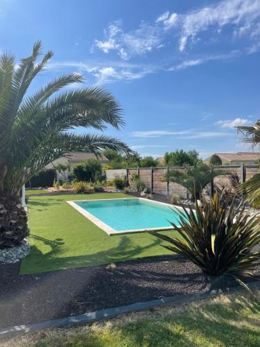 a swimming pool in a yard with a palm tree at Charmante Maison entre châteaux et océan in Cussac-Fort-Medoc