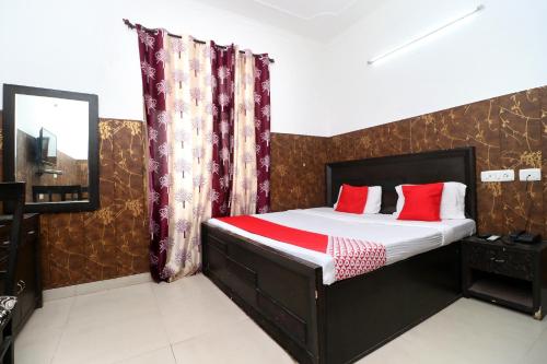 1 dormitorio con 1 cama con almohadas rojas en OYO Flagship 18943 Hotel Punjab Residency en Banūr
