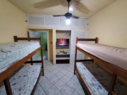 2 Etagenbetten in einem Zimmer mit einem TV in der Unterkunft Apartamento a 4 min a pé da Praia das Castanheiras in Guarapari