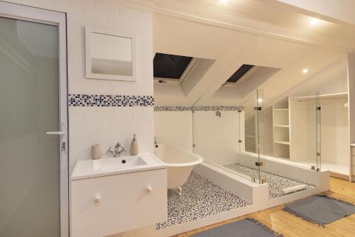 a bathroom with a tub and a sink and a shower at Korhaan House in Melkbosstrand