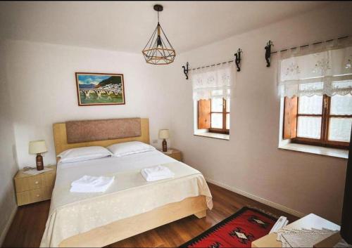 a bedroom with a bed and two windows at Hotel Borklad in Berat