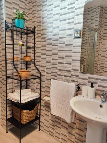 a bathroom with a sink and a shelf with towels at Ático - Piscina Málaga centro in Málaga