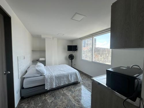 um pequeno quarto com uma cama e uma televisão em Olmo Apartahotel em Pereira