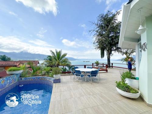 um pátio com uma mesa e cadeiras e o oceano em Casa incrível em Ilhabela com piscina e vista mar em Ilhabela