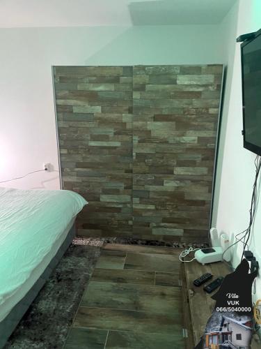 a bedroom with a stone wall and a bed and a television at Villa WOLF in Divčibare