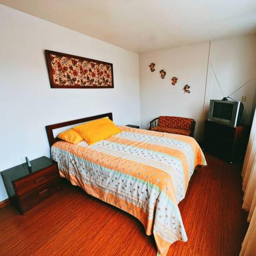 - une chambre avec un lit et une télévision dans l'établissement Departamento Vacacional en el Centro de Loja, à Loja