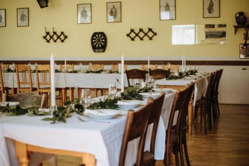 Hospoda na statku في Kadov: طاولة طويلة في غرفة مع طاولات وكراسي بيضاء