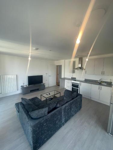 a living room with a couch and a kitchen at New Luxury 2 Bedroom apartment with a beautiful London City view in Barking
