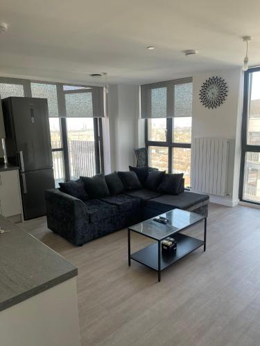 a living room with a black couch and a table at New Luxury 2 Bedroom apartment with a beautiful London City view in Barking