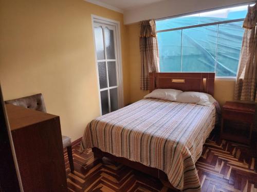 a bedroom with a bed and a large window at HOSPEDAJE FESTEJOS in Juliaca