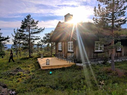 una casa con una terraza con el sol brillando en ella en Solehøgda 71. Unik tømmerhytte som er håndlaget en Surteberg