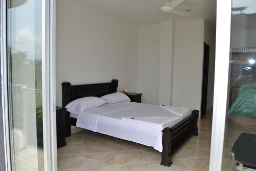 1 dormitorio con 1 cama con sábanas y almohadas blancas en hotel brasil, en Puerto Boyacá