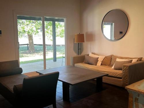 ein Wohnzimmer mit einem Sofa, einem Tisch und einem Spiegel in der Unterkunft Casita de campo en Capilla del Señor in Capilla del Señor
