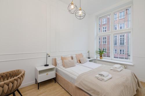 biała sypialnia z łóżkiem i 2 oknami w obiekcie Gdansk Apartments w Gdańsku