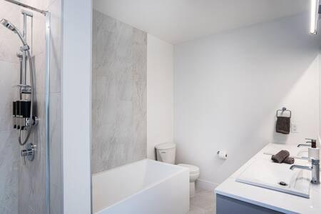 a white bathroom with a tub and a toilet at Mountain Revelation - Stunning Condo in Revelstoke in Revelstoke