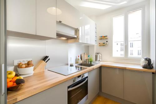une cuisine avec des armoires blanches et un comptoir en bois dans l'établissement Appartement 2 pièces avec vue Tour Eiffel, à Paris