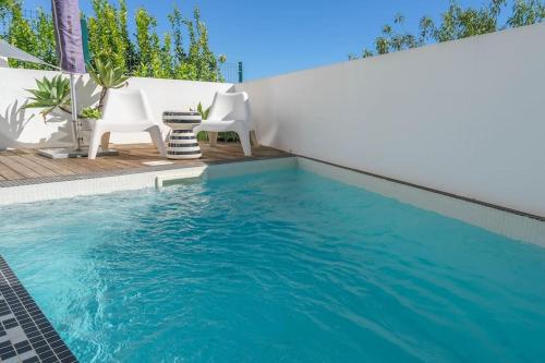 een zwembad met twee witte stoelen ernaast bij Unique Townhouse ~ Private pool ~ Rooftop terrace in Luz