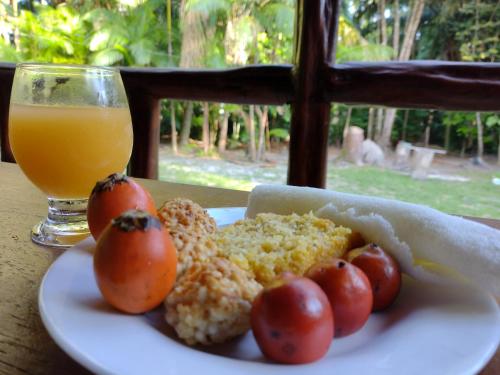 a plate of food with tomatoes and a glass of orange juice at Casa da mata marajó in Salvaterra