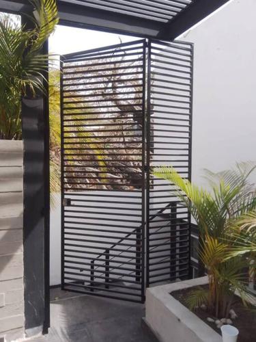 a black metal gate on a building with plants at Residencia Corinto La Cima Frac Burgos Bugambilias in Temixco