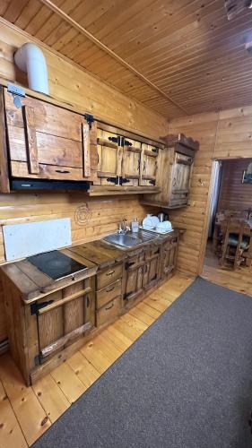 a kitchen with wooden cabinets and a sink in a cabin at Порядна Ґаздиня in Yaremche